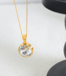 Macro shot of faceted round glass pendant with polished gold plated chain necklace