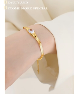 Detail of gold snake chain bracelet featuring an oval clear zircon and adjustable link