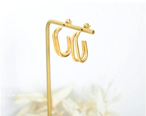 Dettaglio orecchini geometrici a U placcati in oro 18K su un espositore professionale