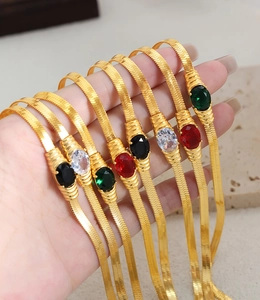 Close-up of golden herringbone necklaces with emerald and ruby zircon pendants