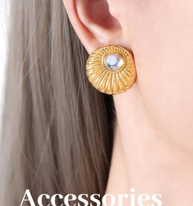 Detail of vintage gold-plated stud earring with radial texture and crystal center