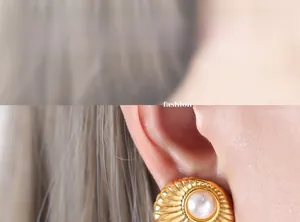 Close-up of retro shell-shaped gold earrings with white pearl inlay on model ear