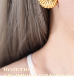 Detail of vintage gold-plated shell earrings with radial textured relief and glossy finish