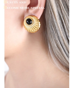 Macro shot of vintage gold shell earrings with a black cabochon stone inlay