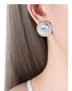 Macro detail of silver shell-textured stud earring with iridescent moonstone center
