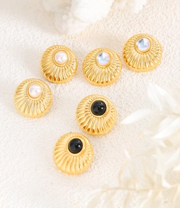 Detail view of retro gold stud earrings with pearls and moonstones on textured background