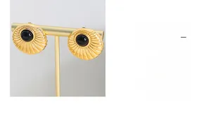 Detail of vintage gold shell earrings with black center stone on a jewelry display stand