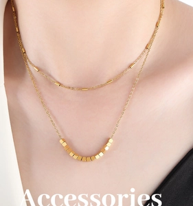 Gros plan d'un collier double épaisseur doré avec perles carrées sur le cou