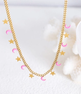 Dettaglio ravvicinato della collana d'oro con ciondoli a luna in smalto rosa e stelle