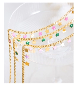 Dettaglio della collana dorata con ciondoli a stella smaltati in rosa e verde vivace