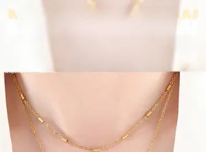 Détail d'un collier doré minimaliste avec perles cylindriques porté par un mannequin