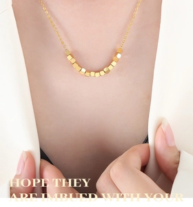 Détail d'un collier doré minimaliste avec perles carrées sur le cou d'un mannequin