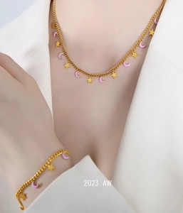 Dettaglio del set collana e bracciale dorati con ciondoli a stella e luna viola