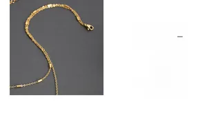 Gros plan sur un collier double rang doré en titane avec pendentifs cylindriques et fermoir