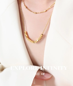 Détail d'un collier chic à double couche doré avec perles géométriques et pendentifs