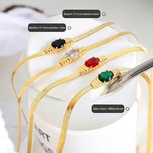 Elegant gold snake chain jewelry set with colorful oval stones on white ceramic cup