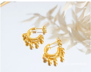 Détail de boucles d'oreilles en titane doré avec perles pendantes sur miroir