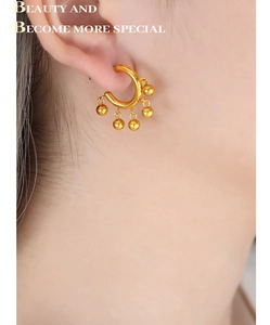 Gros plan d'une boucle d'oreille créole dorée en C avec cinq perles sur un mannequin