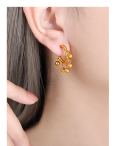 Gros plan de boucles d'oreilles créoles dorées avec cinq petites perles rondes suspendues