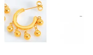 Gros plan de boucles d'oreilles en C plaquées or avec cinq perles métalliques suspendues