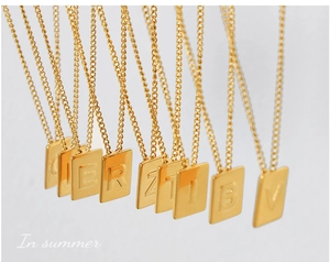 Detail showing multiple rectangular gold-plated letter pendants on thin chains