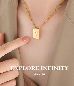 Detail of a gold square pendant necklace with an engraved letter Y on a link chain