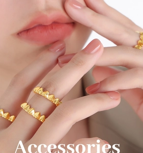 Dettaglio di un anello dorato con trama triangolare indossato al dito per un look chic