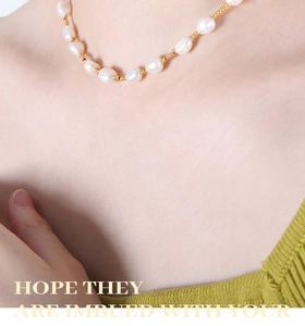 Detail of freshwater pearl necklace with gold beads on model wearing green knitwear