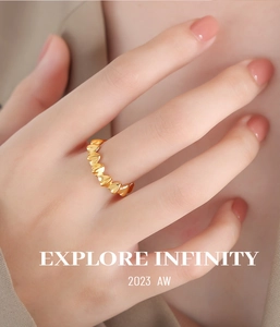 Dettaglio dell'anello dorato con cuori intrecciati indossato da una modella con stile