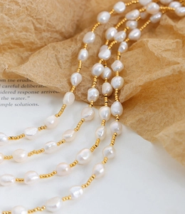 Detailed view of Baroque freshwater pearls mixed with tiny gold beads on a soft backdrop
