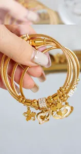 Close-up of gold cable texture bangles with heart and clover zircon-set charms