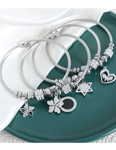Silver-plated wire rope bracelets set with clover, star, and heart charms in a ceramic dish