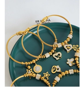 Close-up of gold cable bracelets with zircon charms and Love heart pendant on a tray