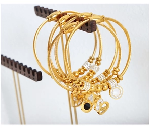 Close-up of golden steel wire bracelets with heart and shell charms on a wooden display