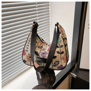 Close-up of vintage floral knit hobo bag with a black leather logo and adjustable strap