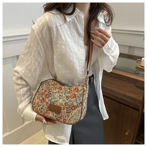 Floral embroidery detail and leather trim on vintage linen crossbody bag worn by model