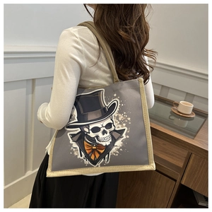 Detail shot of a grey tote bag with skull illustration and textured woven handles