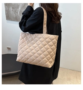 Close-up of beige quilted tote bag with large diamond stitching and padded texture