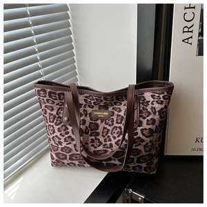 Detailed view of leopard print tote bag with brown leather handles and golden metal logo
