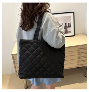 Quilted black tote bag detail showing shoulder fit and spacious nylon texture