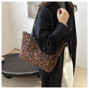 Side view of leopard print tote bag worn with a black coat and white pants