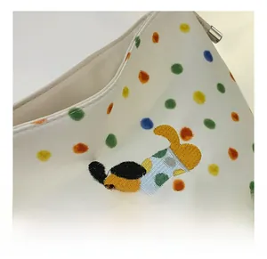 Detailaufnahme der weißen Polka-Dot-Tasche mit bunten Punkten und Welpen-Stickerei