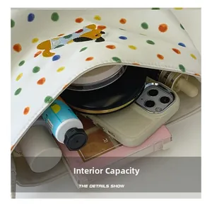 Geräumiges Innere der weißen Polka-Dot-Stofftasche mit Kosmetik und Smartphone