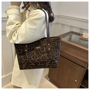 Detail of leopard print tote bag with leather straps on a model in a modern interior