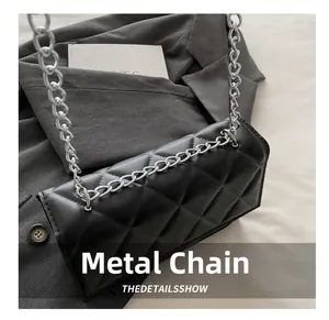 Detail of silver chain strap attachment on black quilted faux leather crossbody bag