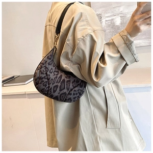 Close-up of leopard print shoulder bag with black leather strap and gold metal hardware