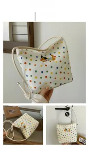 Detailaufnahme der beigen Canvas-Schultertasche mit bunten Punkten und Hundestickerei