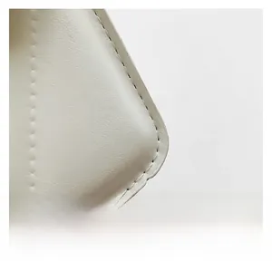 Gros plan détaillé montrant la texture du cuir et les coutures précises du sac blanc