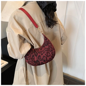 Detail of leopard print half-moon shoulder bag with red strap and gold metal buckles