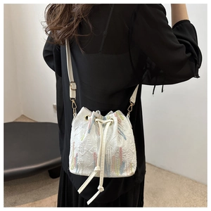 Detail of white nylon bucket bag with rainbow stripes and drawstring closure shown on model